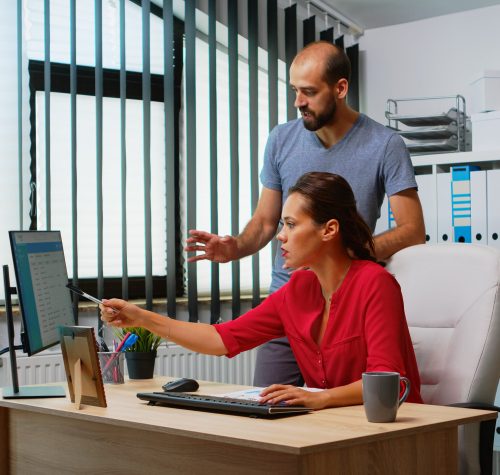 Team searching the best solution in front of computer in modern office room. Coworkers discussing working in workplace in personal corporate company typing on pc keyboard pointing at desktop